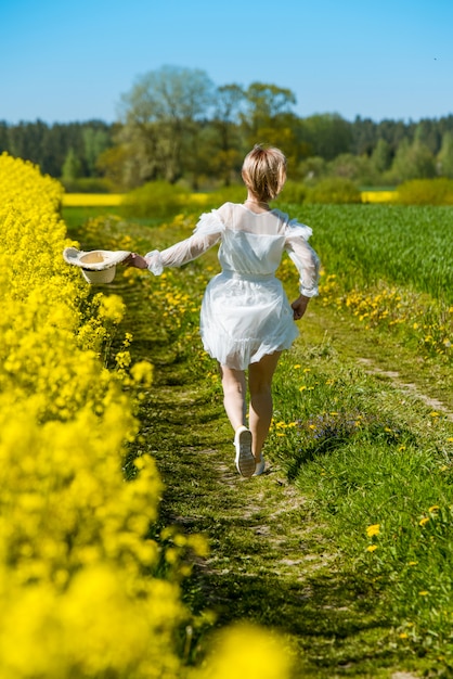 La giovane donna sta in un campo giallo