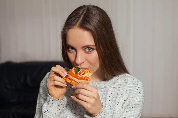 La giovane donna sta mangiando la pizza calda