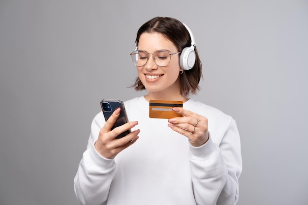 La giovane donna sta pagando l'abbonamento alla musica per telefono con carta di credito