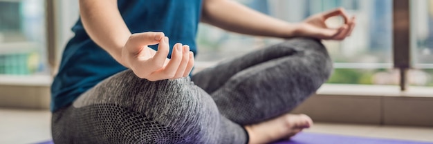 La giovane donna sta praticando lo yoga al mattino sul suo balcone con una vista panoramica della città e dei grattacieli BANNER formato lungo