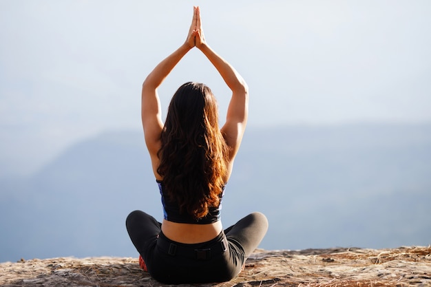 La giovane donna sta praticando lo yoga in montagna in estate