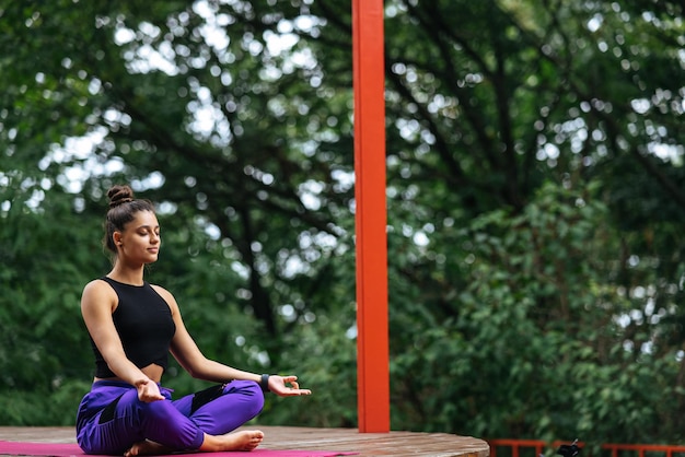 La giovane donna sta praticando lo yoga seduto nella posizione del loto