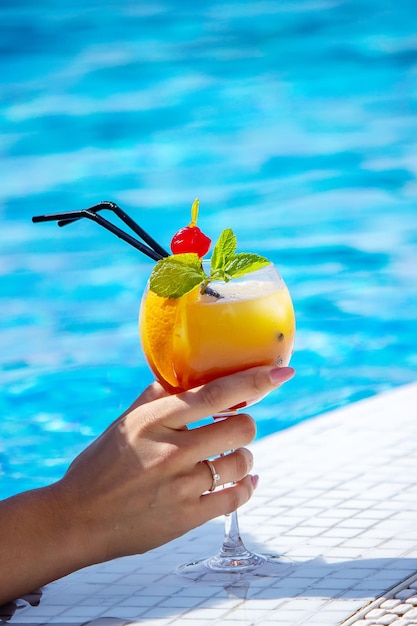 La giovane donna sta riposando in piscina. Beve un cocktail con un'arancia appena spremuta.