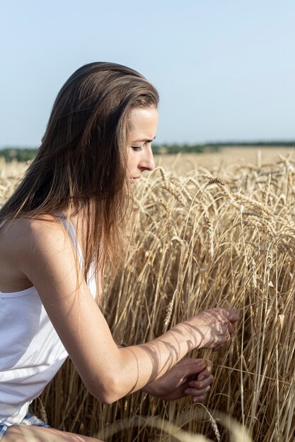 La giovane donna sta strappando le spighette di grano in un campo di grano.