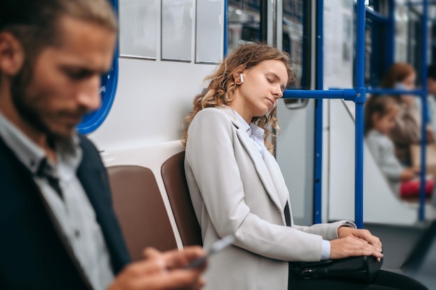 La giovane donna stanca dorme su un treno della metropolitana