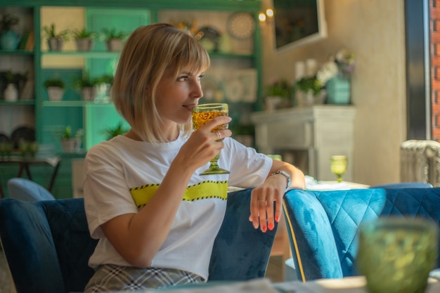 La giovane donna sveglia beve il succo in cafe