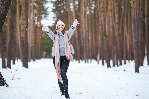 La giovane donna sveglia sta giocando con la neve nella foresta Natura di emozioni di felicità di stile di vita di inverno