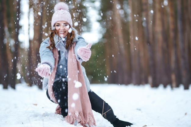 La giovane donna sveglia sta giocando con la neve nella foresta Natura di emozioni di felicità di stile di vita di inverno