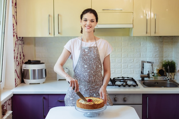 La giovane donna taglia una torta in cucina