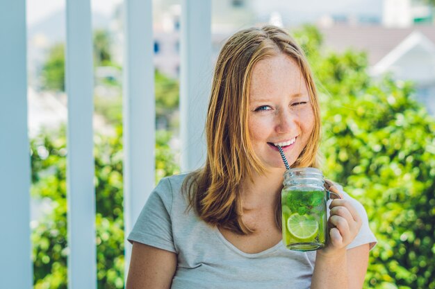 La giovane donna tiene in mano un barattolo di vetro con un mojito