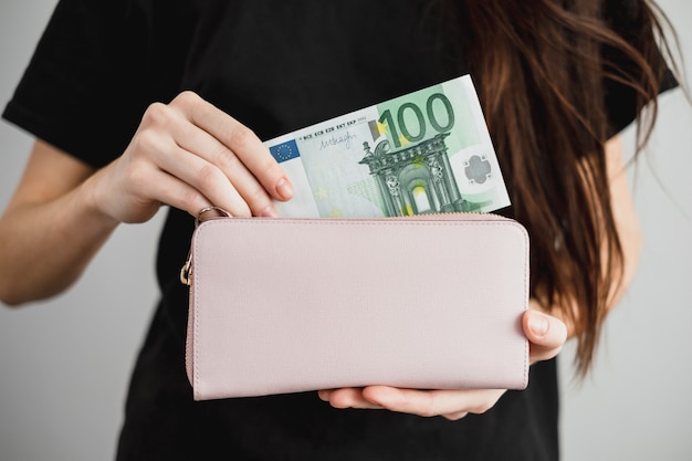 La giovane donna tira fuori i soldi da un portafoglio in pelle