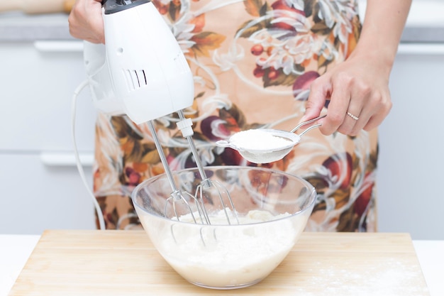 La giovane donna usa il mixer per sbattere le uova, si trova in una cucina moderna