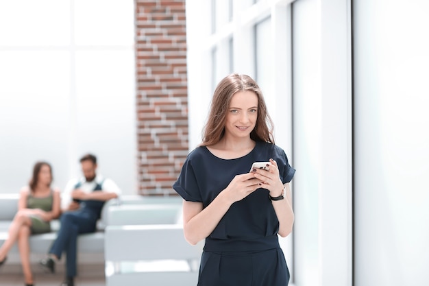 La giovane donna usa il suo smartphone in ufficio .foto con spazio di copia