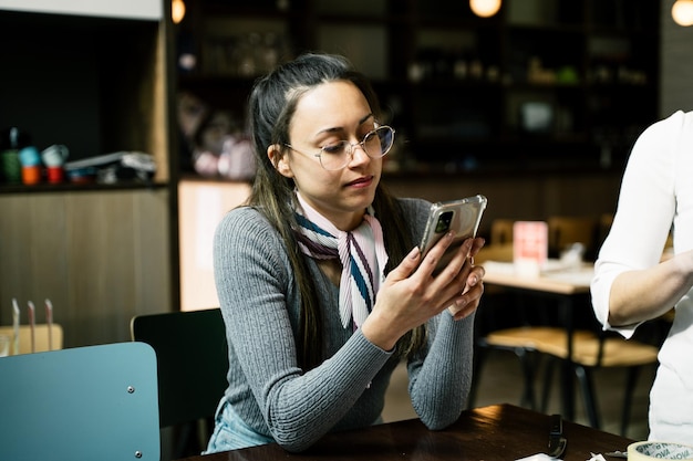 La giovane donna utilizza uno smartphone in un concetto di Internet banking per lo shopping online di caffè