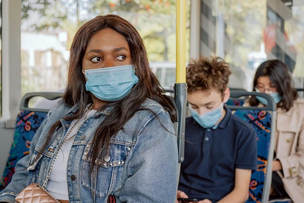 La giovane donna vestita con una giacca di jeans si siede sul trasporto pubblico di autobus