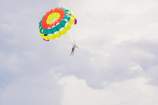 La giovane donna vola su un paracadute tra le nuvole.