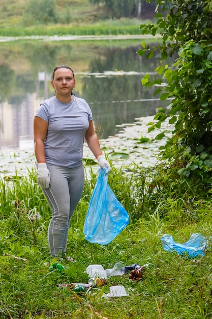 La giovane donna volontaria pulisce la spazzatura in una discarica nel parco. Foto verticale