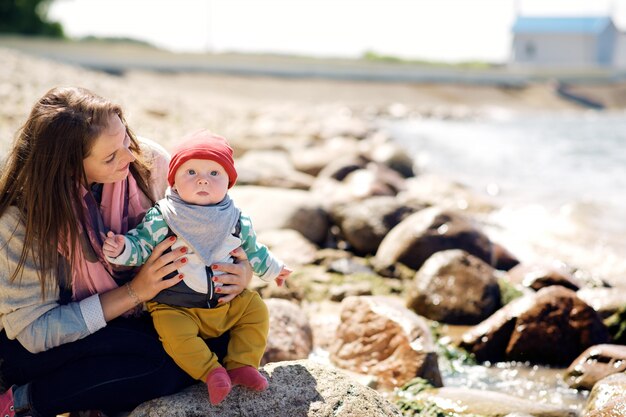 La giovane e felice madre si prende cura del suo giovane figlio e cammina lungo la riva del lago