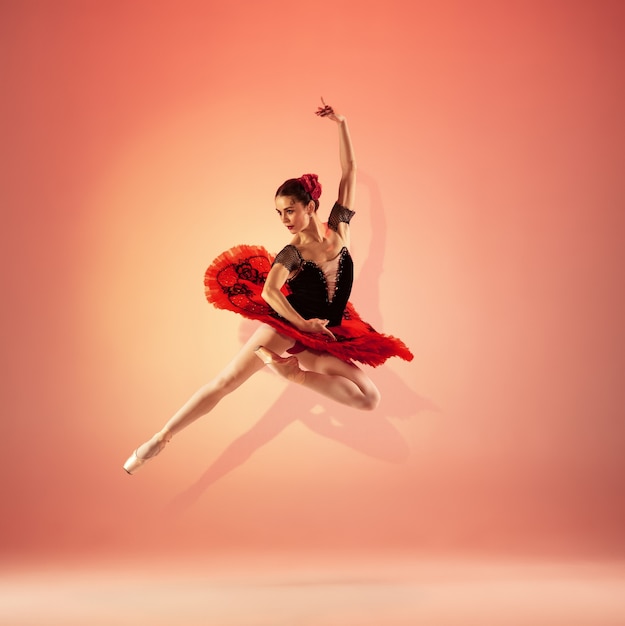 La giovane e incredibilmente bella ballerina sta posando e ballando nello studio rosso pieno di luce.