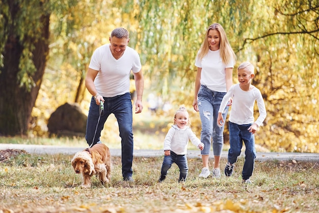 La giovane famiglia allegra fa una passeggiata insieme in un parco autunnale.