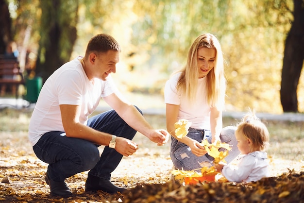 La giovane famiglia allegra si riposa insieme in un parco autunnale.