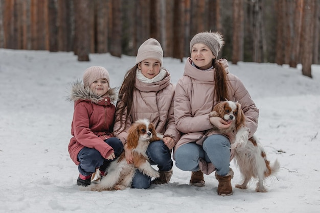 La giovane famiglia caucasica felice gioca con i cani in inverno in una foresta di pini