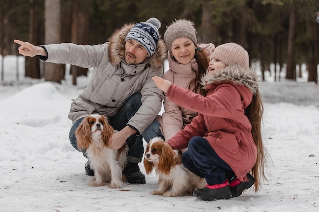 La giovane famiglia caucasica felice gioca con un cane in inverno in una foresta di pini