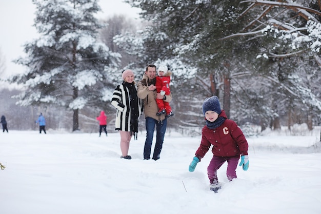 La giovane famiglia con bambini sta camminando nel parco invernale. Passeggiata invernale di genitori con bambini. Camminare durante il fine settimana di vacanza in inverno.