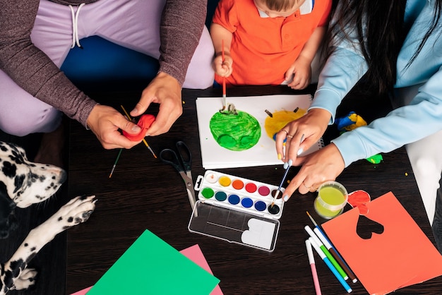 La giovane famiglia con un cane fa un lavoro creativo a casa, dipinge e scolpisce con la plastilina