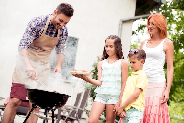 La giovane famiglia fa il barbecue a casa loro