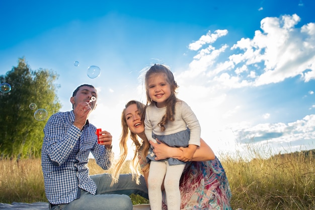 La giovane famiglia felice cammina nella natura, al tramonto