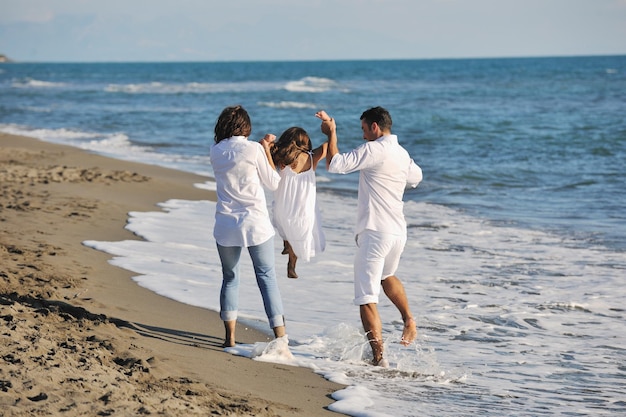 la giovane famiglia felice in abiti bianchi si diverte in vacanza sulla bellissima spiaggia