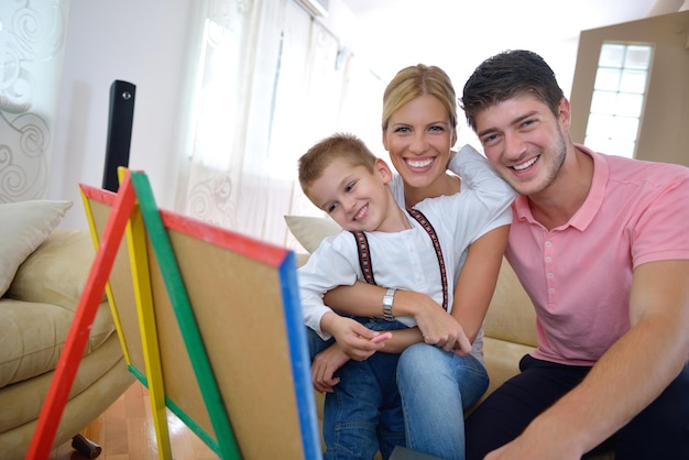 la giovane famiglia felice insegna lezioni e prepara il figlio per la scuola mentre disegna a bordo a casa