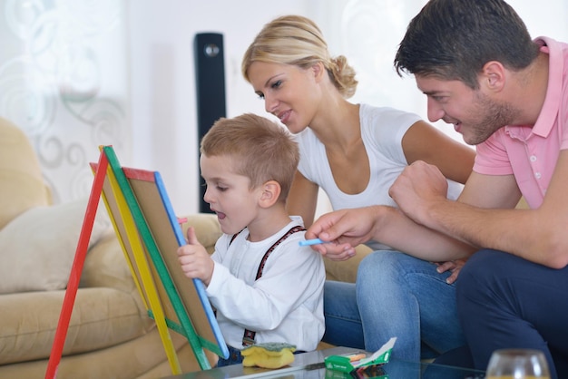 la giovane famiglia felice insegna lezioni e prepara il figlio per la scuola mentre disegna a bordo a casa