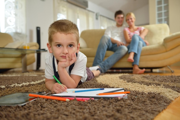 la giovane famiglia felice insegna lezioni e prepara il figlio per la scuola mentre disegna a bordo a casa