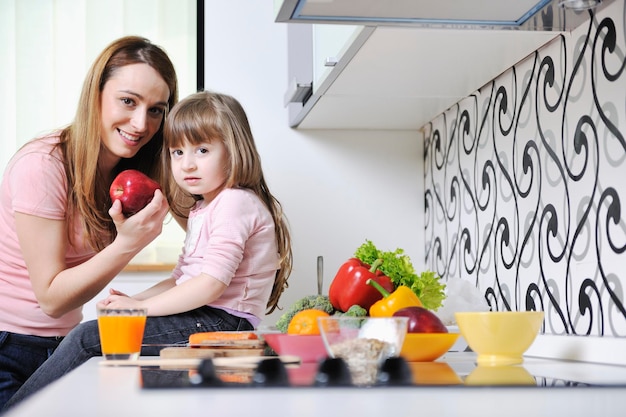 la giovane famiglia felice pranza con frutta fresca e verdura in una cucina luminosa