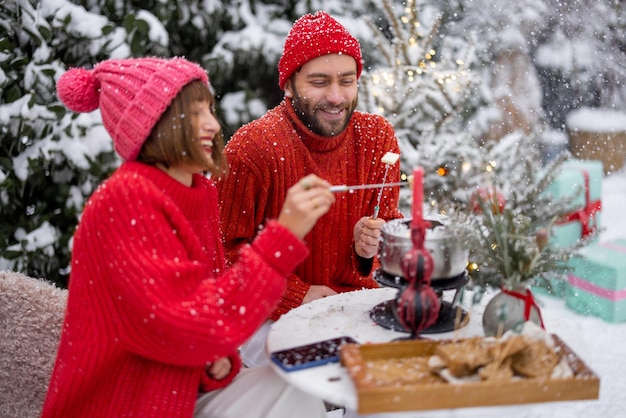 La giovane famiglia ha una cena romantica durante le vacanze invernali all'aperto