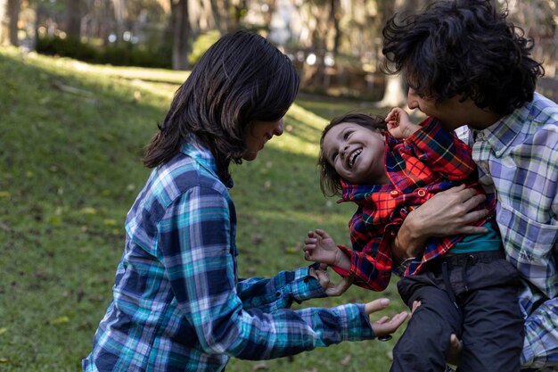 La giovane famiglia latinoamericana trascorre il pomeriggio nel parco mentre gioca felicemente con il loro bambino di 3 anni Concetto di famiglia