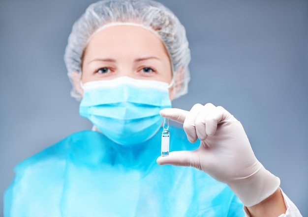 La giovane infermiera con una maschera medica posa davanti alla telecamera su un tema medico