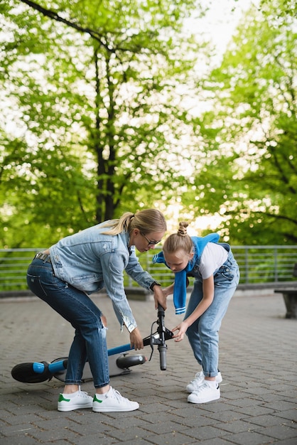 La giovane madre aiuta sua figlia dopo la caduta dell'e-scooter nel parco cittadino