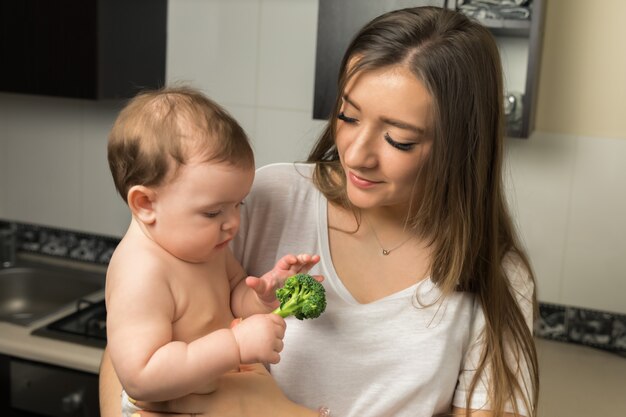 La giovane madre alimenta i broccoli del bambino.