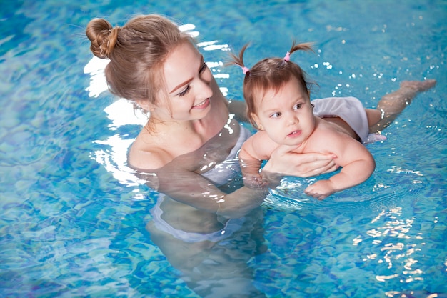 La giovane madre bagna il bambino in piscina.