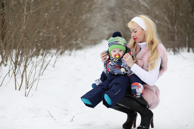 La giovane madre cammina in una giornata invernale con un bambino in braccio nel parco