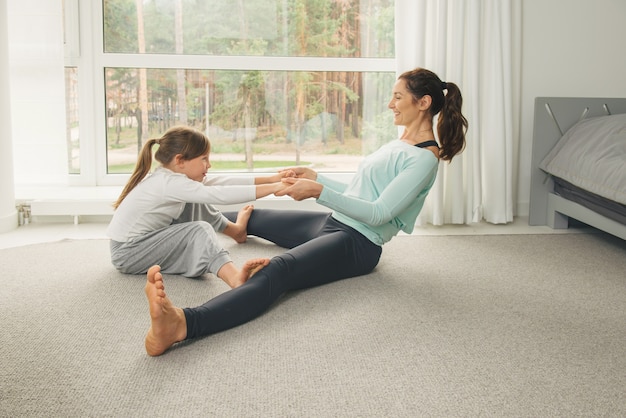 La giovane madre e figlia che fanno l'yoga di mattina si esercitano