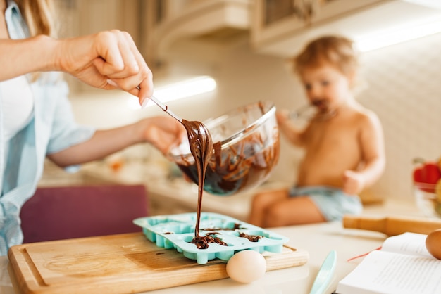 La giovane madre e il bambino preparano la pasticceria e assaggiano il cioccolato fuso.