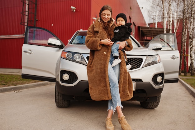 La giovane madre e il bambino stanno vicino loro suv auto. Concetto di guida di sicurezza.