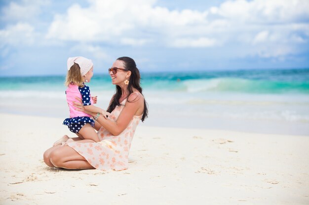 La giovane madre e la sua piccola figlia si divertono sulla spiaggia tropicale