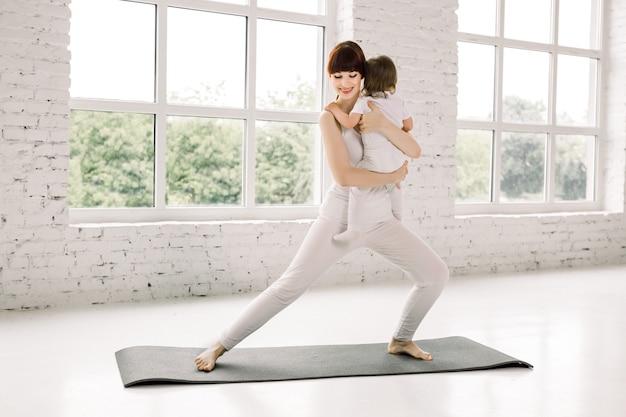 La giovane madre fa esercizi di yoga fisica insieme al suo bambino. madre con bambino facendo ginnastica ed esercizi