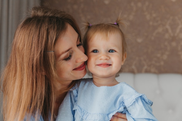 La giovane madre felice gioca con sua figlia sul letto a casa. festa della mamma.