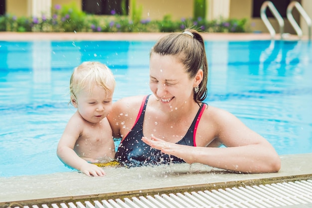 La giovane madre insegna al suo figlioletto come nuotare in una piscina